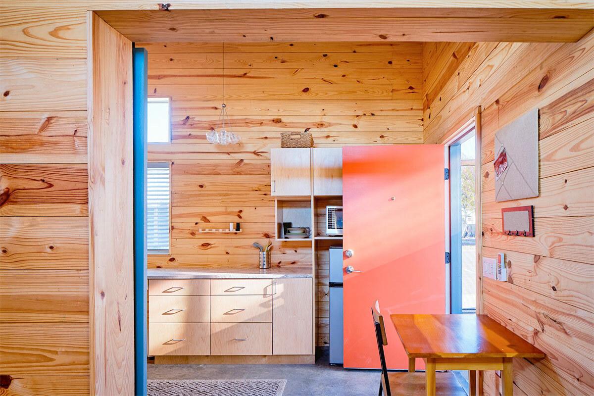 interior of a tiny home with wood planks on the walls and a small table and chair.