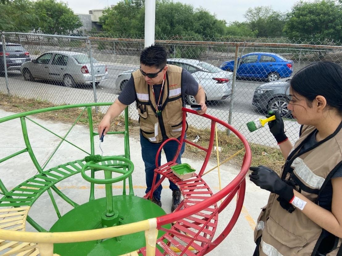 Volunteers painting a piece of playground equipment.