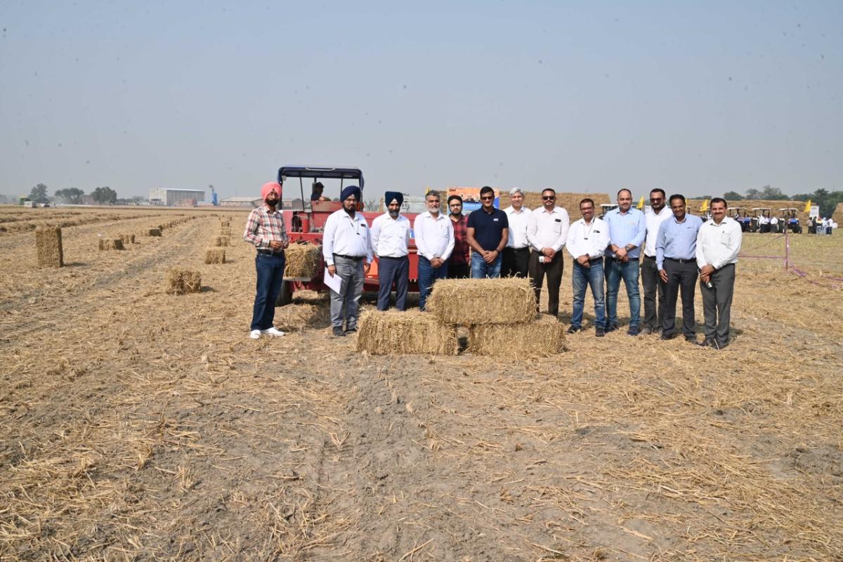 Farmers standing behind bales of straw