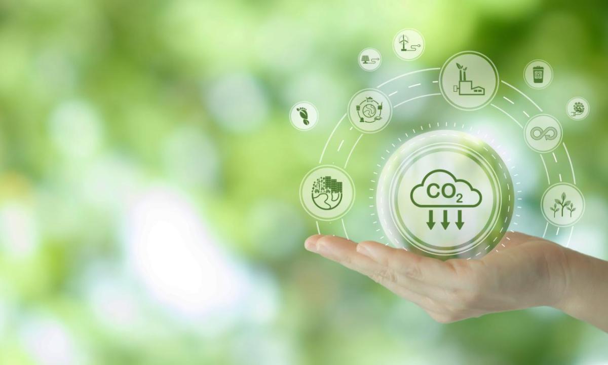 A hand against a green background, with illustrations of CO2 emissions