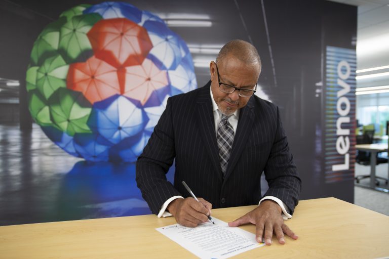 Calvin Crosslin standing at a table, signing a document
