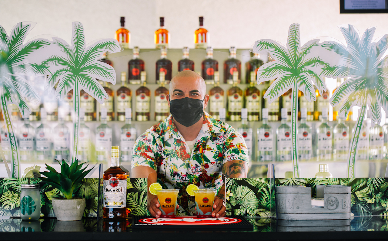 Image of a bartender serving drinks while wearing a face mask