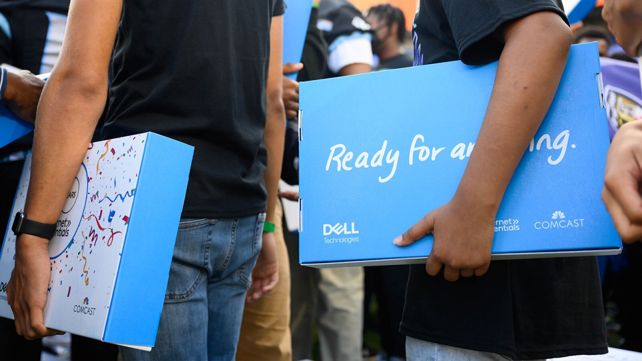 students holding laptop boxes