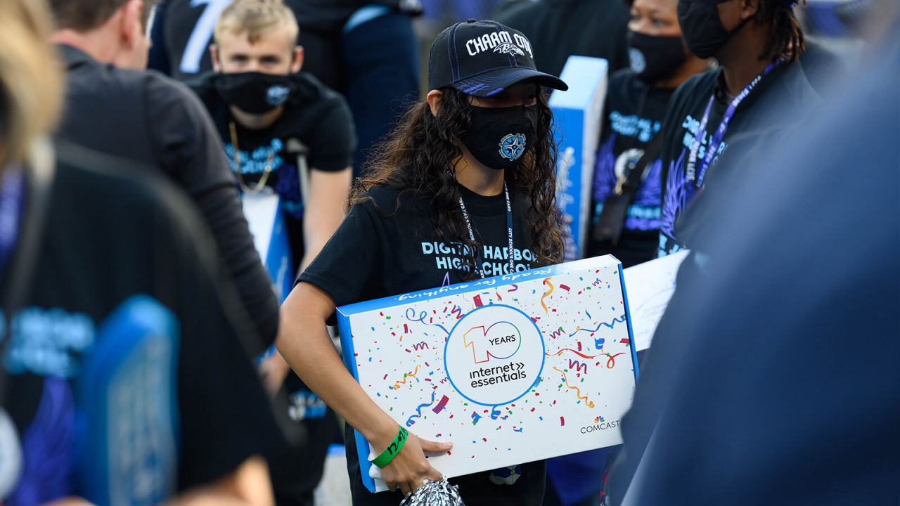 Masked student holding laptop box