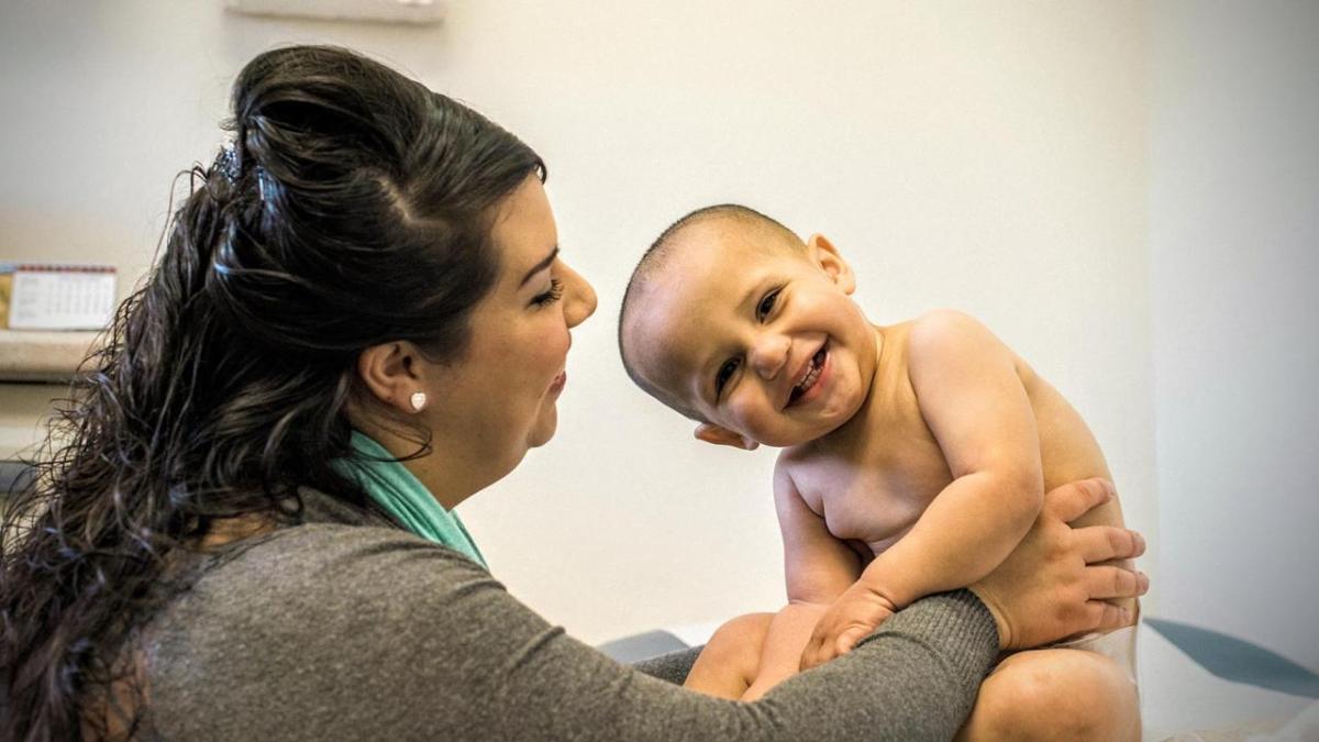 A woman and an infant smile in a doctor's office at a community health center.