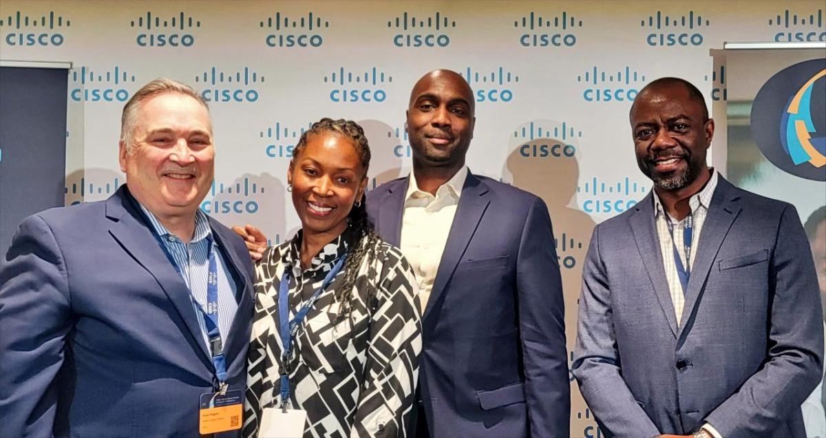 Four people stood in front of a Cisco logo backdrop 