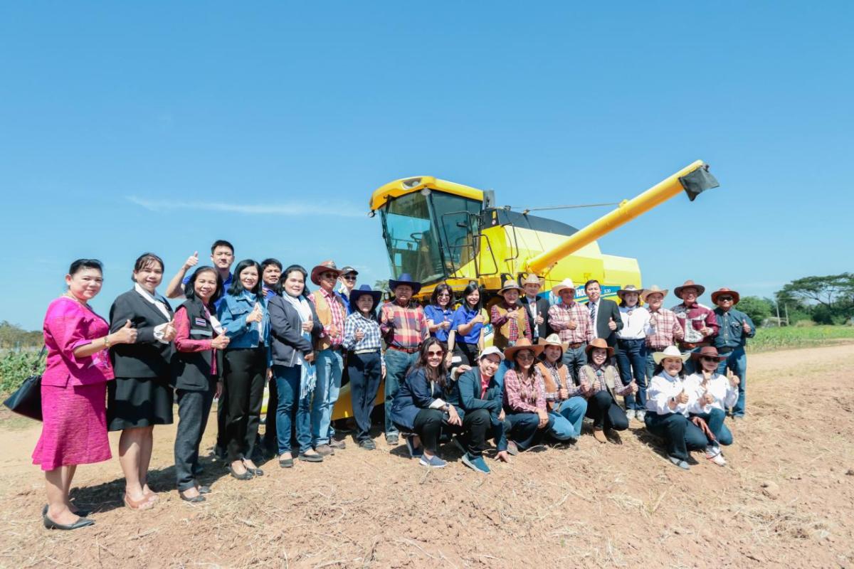 A group of people in front of a yellow harvesting machine.