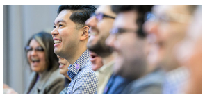 A row of smiling people, focused on one in the middle.