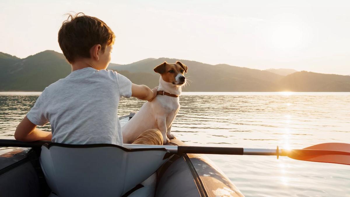 Young boy sitting in a canoe with his dog on a lake.
