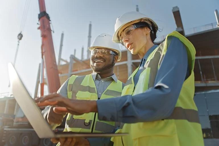 Two people looking at a tablet outside of a glass office building