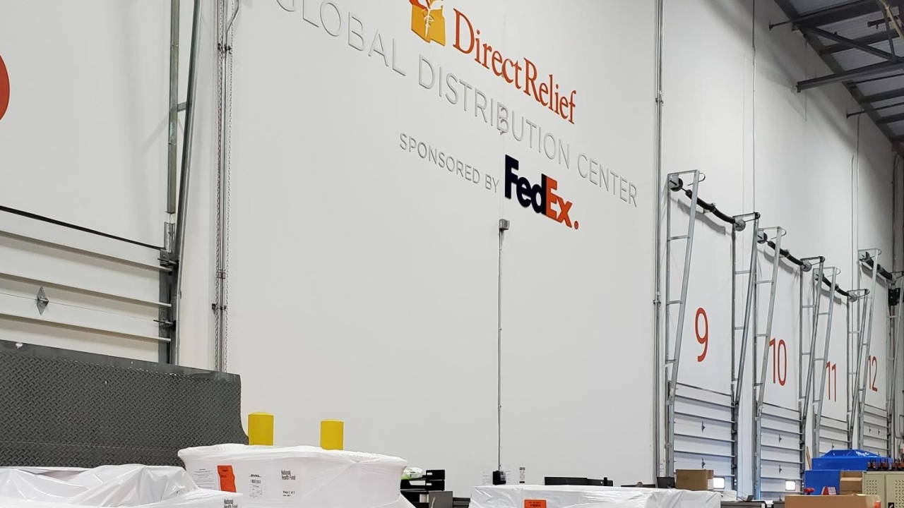 Large bay doors, "DirectRelief Global Distribution Center sponsored by FedEx" on the wall.