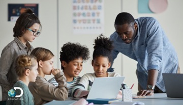 children gathered on a computer surrounded by two adults 