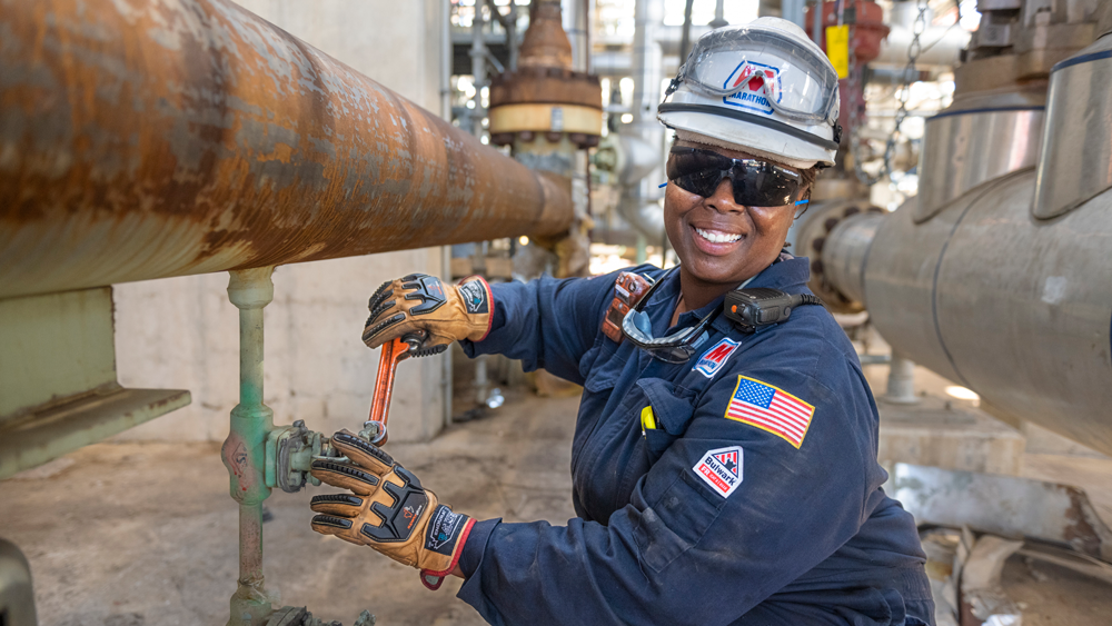 Dynita McCaskill turning a valve on an industrial pipe