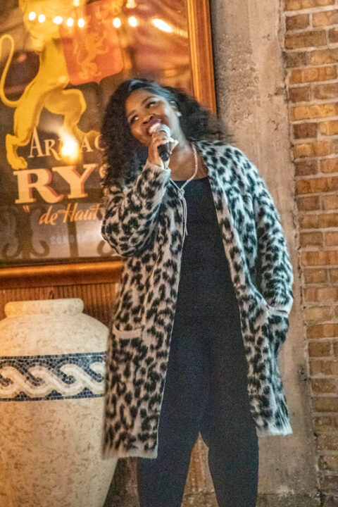 person in long fur jacket speaking into microphone
