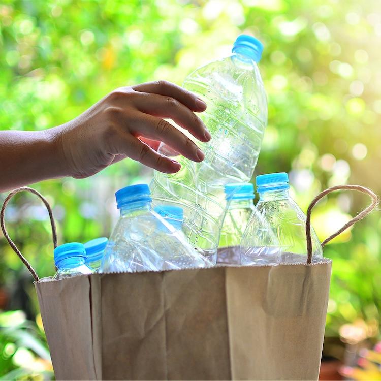 Empty plastic bottles being put into a recycling bag.