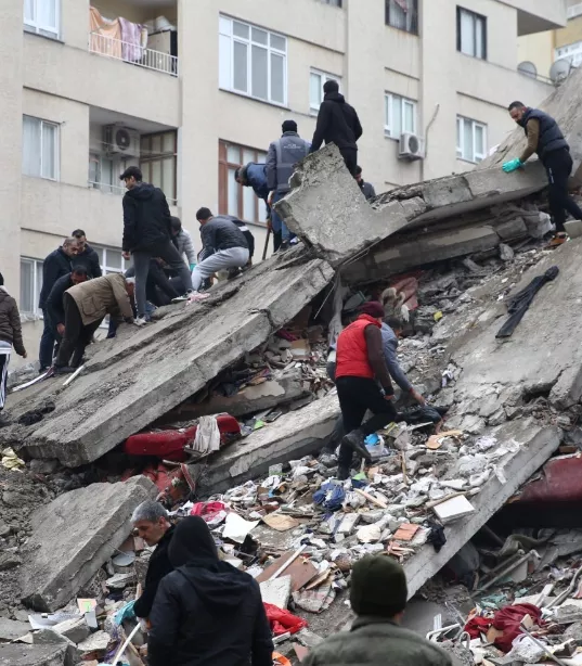 People climbing on top of rubble caused from an earthquake
