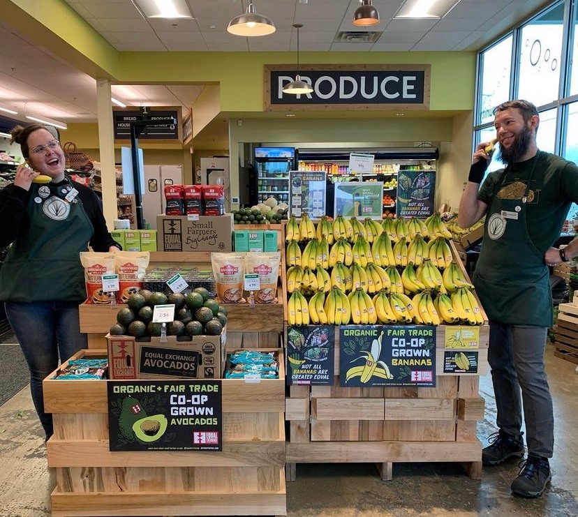 Two workers in a grocery store by banana display