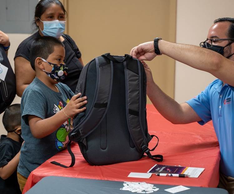 Image of a student being handed a new backpack