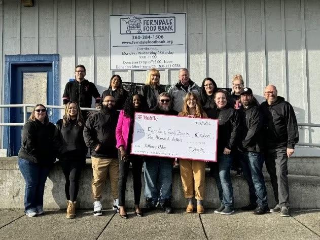 A group of people stood outside Ferndale Food Bank, holding a donation cheque