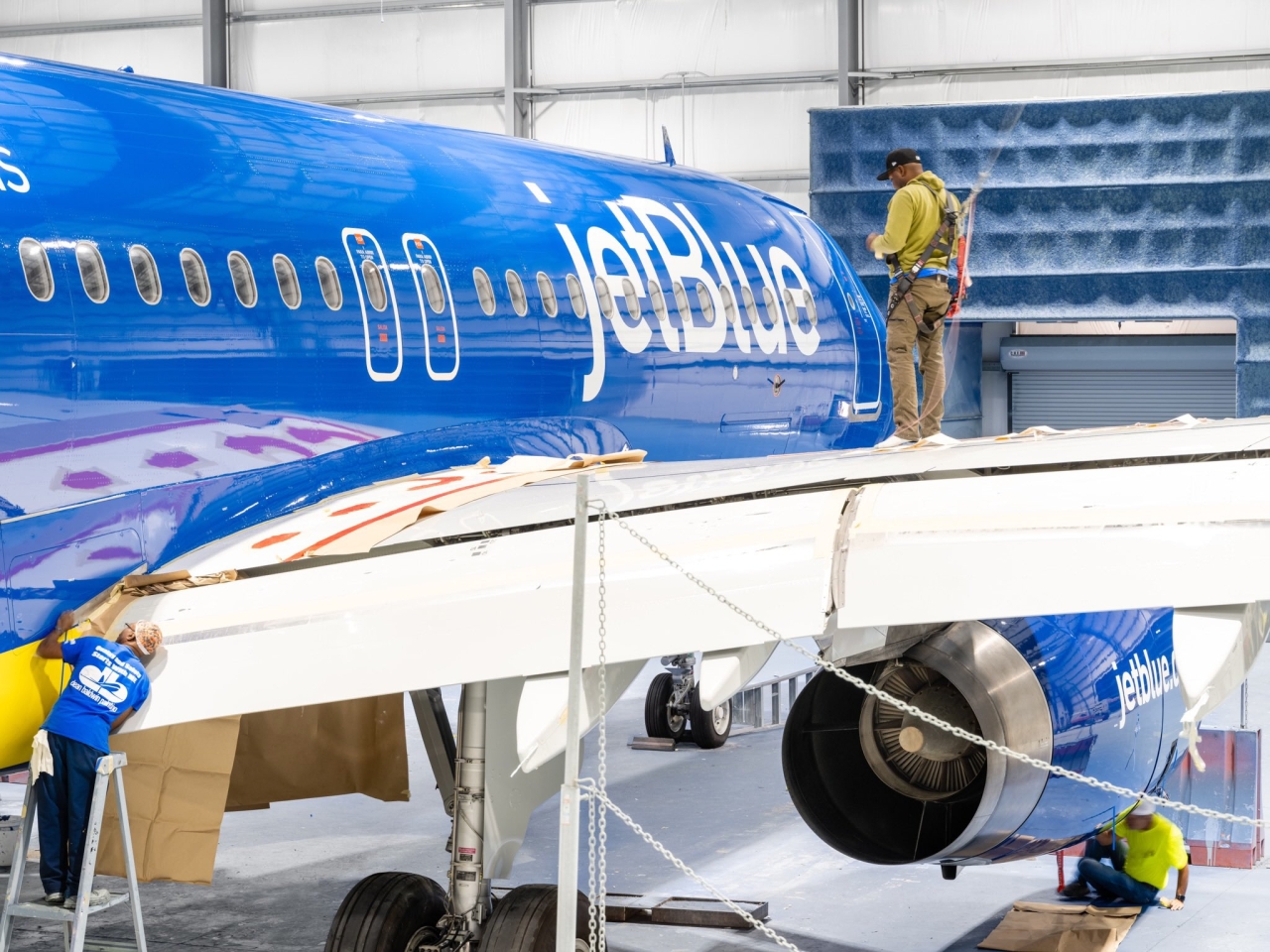 Man working on blue and yellow airplane in hangar