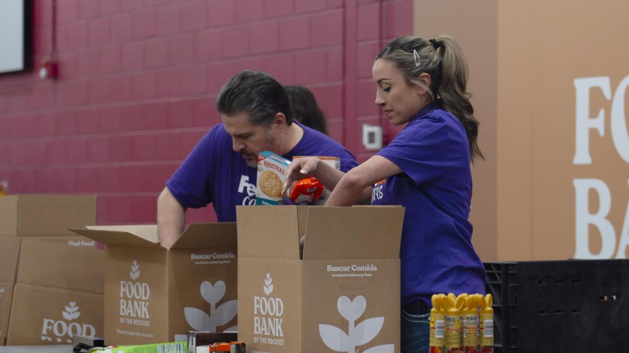Two people wearing FedEx shirts packing boxes at the Food Bank