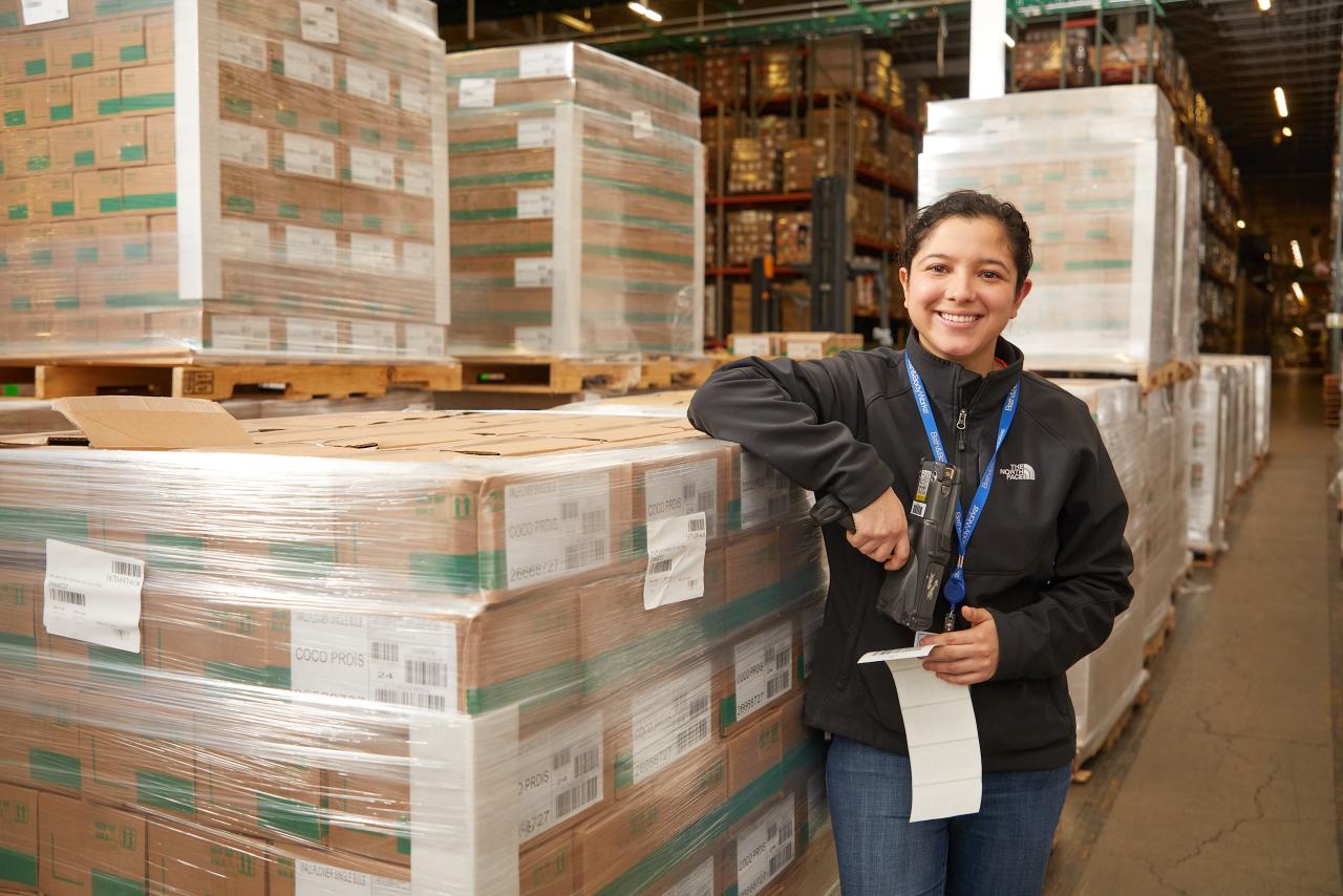 person smiling next to a warehouse of boxes