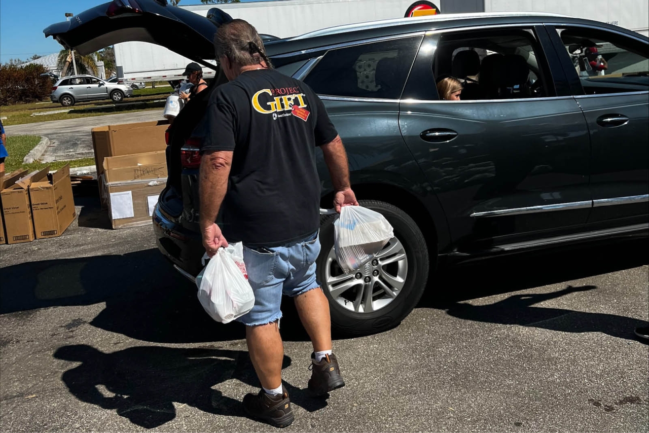 a person with bags in their hands loading the trunk of a car