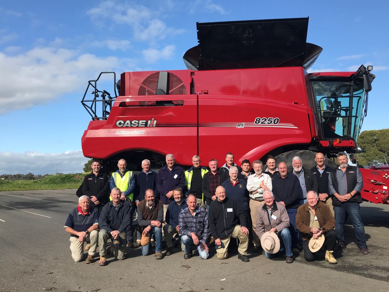 grain harvester with large group of people in front