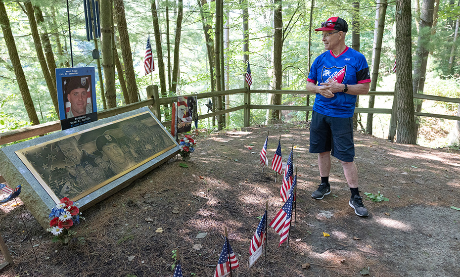 Gene Griffin standing in front of his son's memorial, American flags decorate it