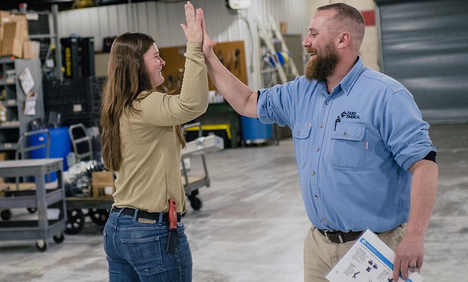 Georgia Hummel give a coworker a high-five in a warehouse