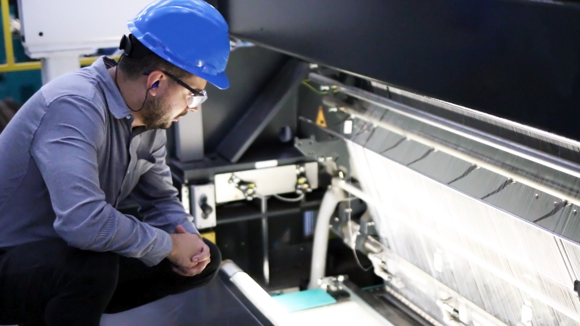 Glass fiber strands being stitched into fabric for a wind turbine blade