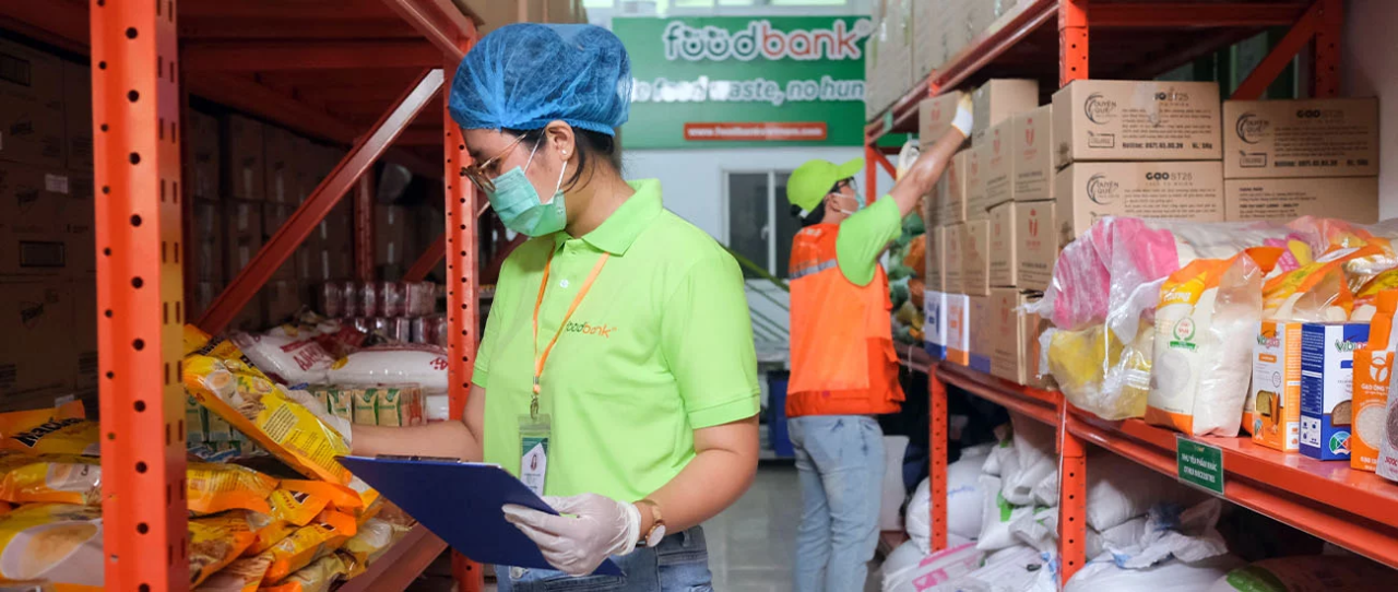 two workers in ppe collecting food items from a warehouse