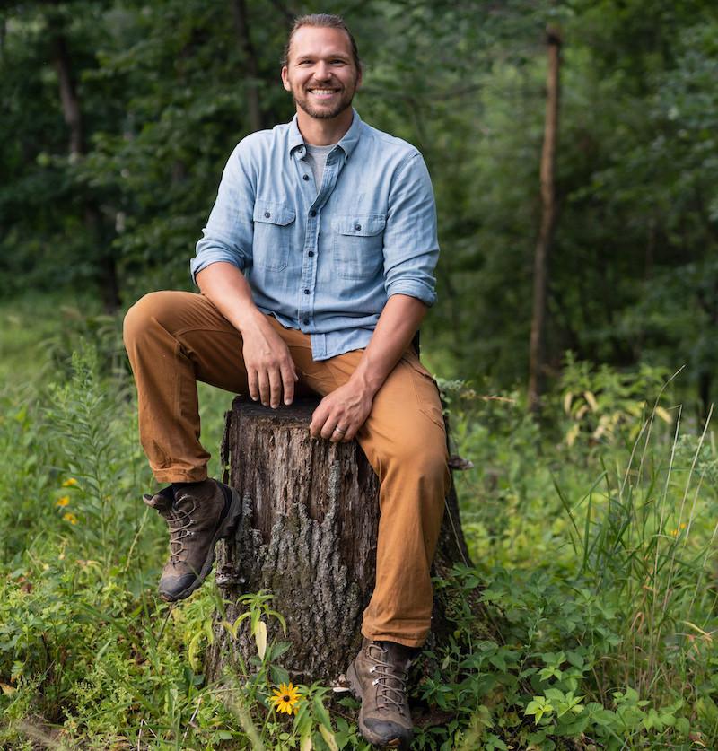 Tim Clemens seated on a stump.