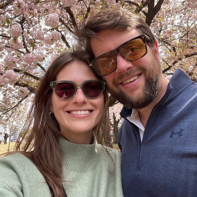 Clement with his wife in front of a flowering tree.