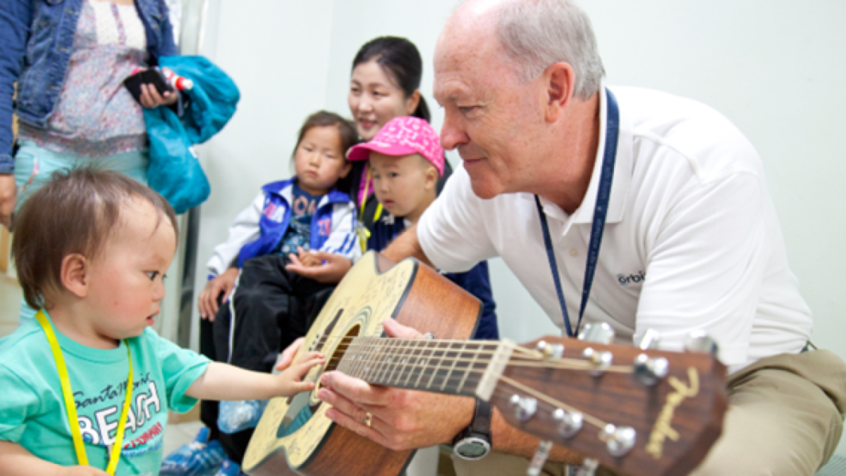 An adult showing a young child a guitar