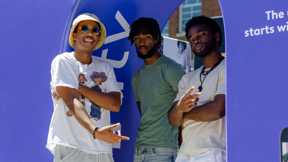 Group of three people stood against a purple background