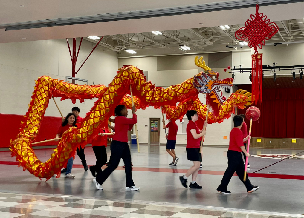 Group of students wearing red performing traditional dragon dance