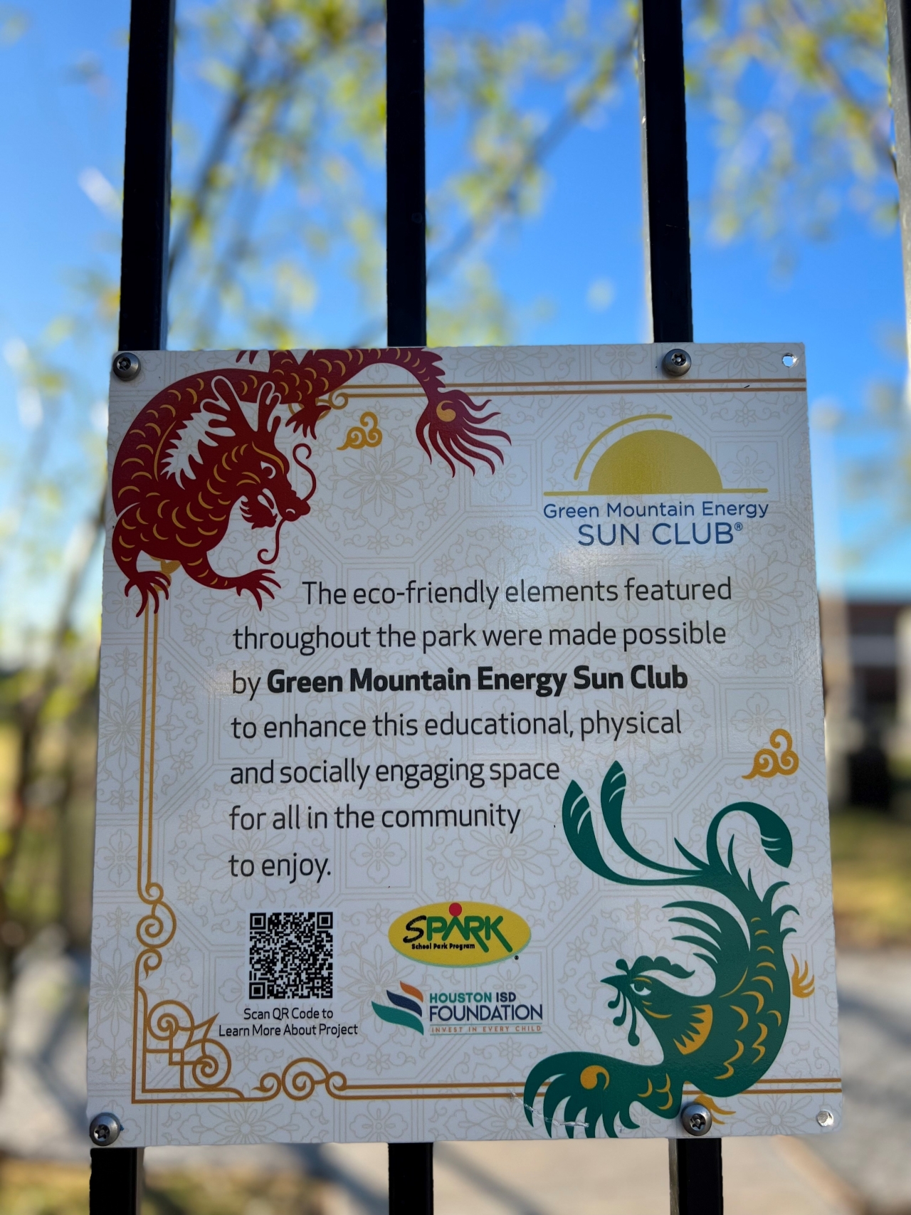 White sign on black fence featuring red and green dragons