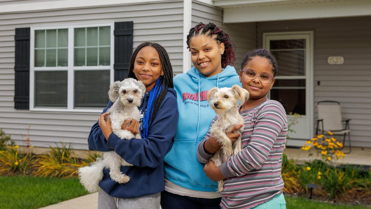 Ambera Pruitt, center, with her daughters Charity and Azaylia, and two family dogs in front of the home Pruitt purchased five years ago from Habitat for Humanity of St. Joseph County. U.S. Bank volunteers worked alongside Pruitt to help build the home.