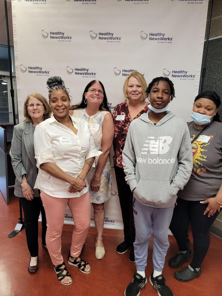 Students stood in front of a Healthy NewsWorks backdrop 