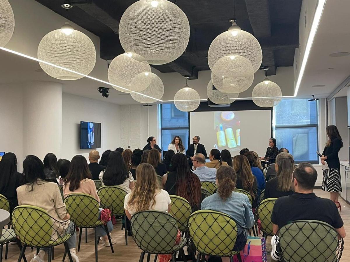 A room full of seated people, three speakers at the front.