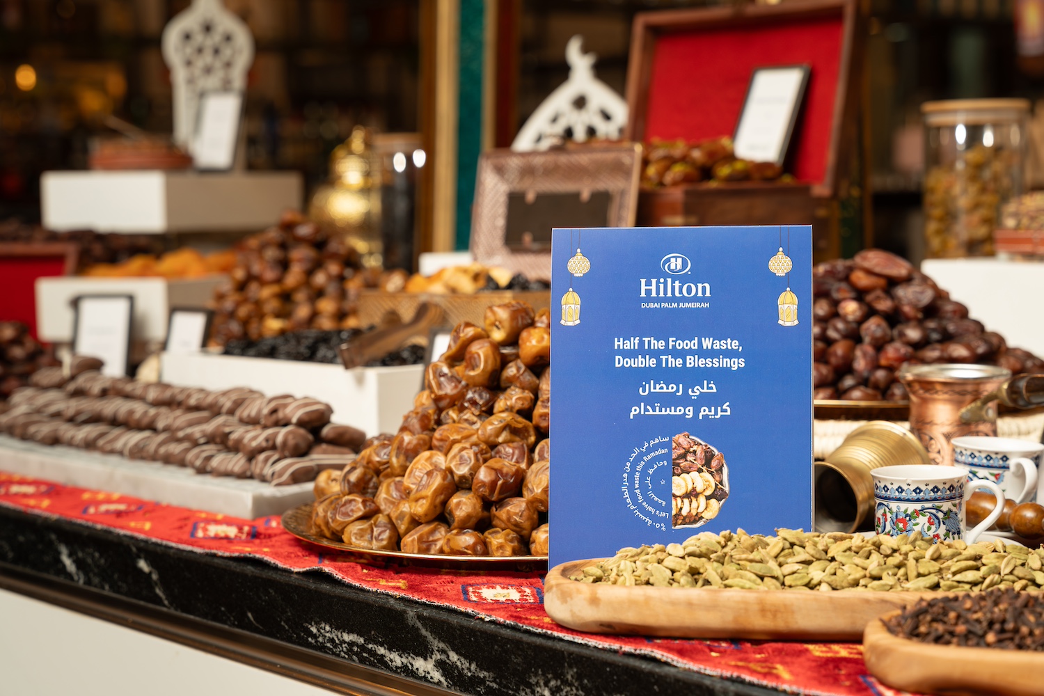 A small sign shares Hilton's Green Ramadan messaging, "Half the food waste, double the blessings," near the hotel buffet.