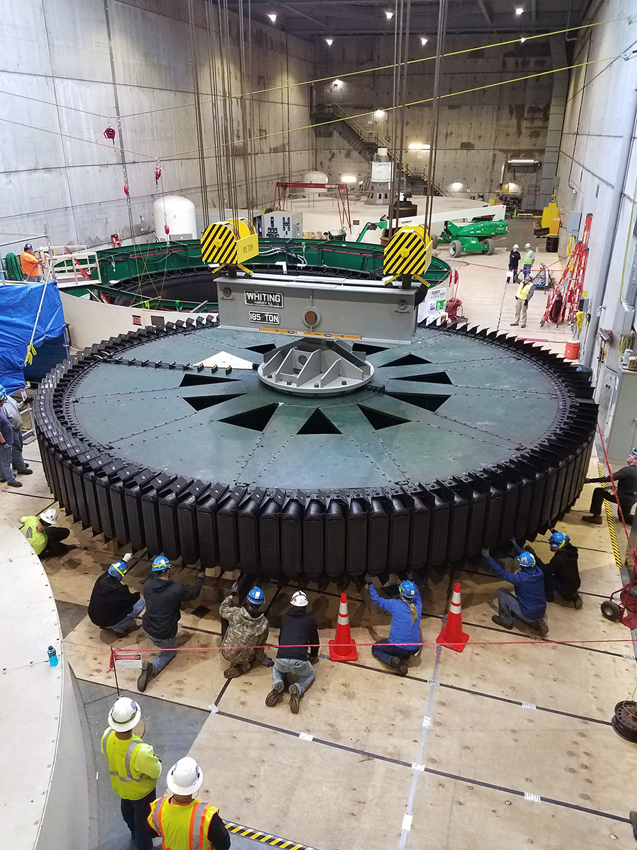 workers surround a large rotor inside a huge complex