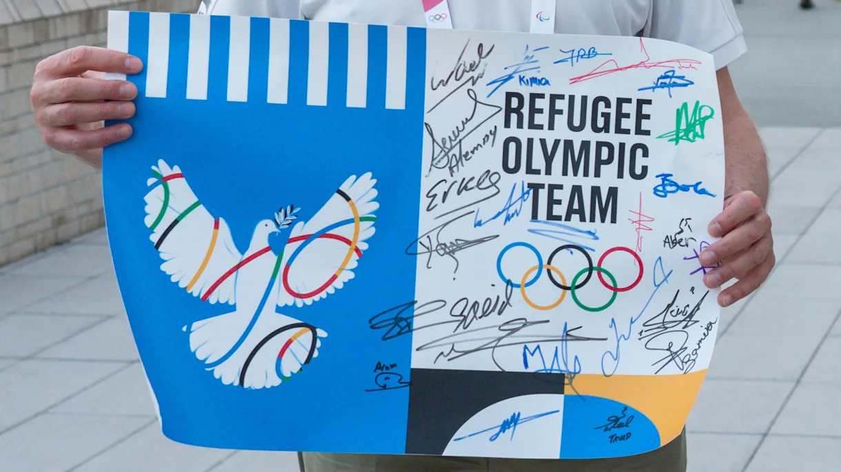 person holding Refugee Olympic Team sign with signatures