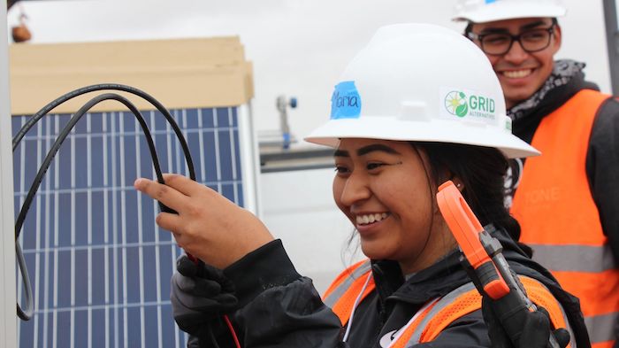 Photo: Courtesy of  GRID Alternatives. Woman in a hard hat working on a solar panel.