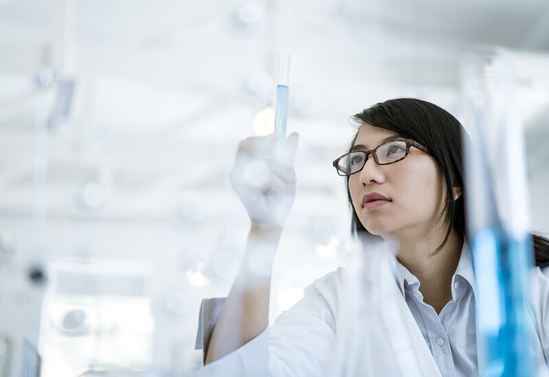 Female scientist in a lab holding a test tube.