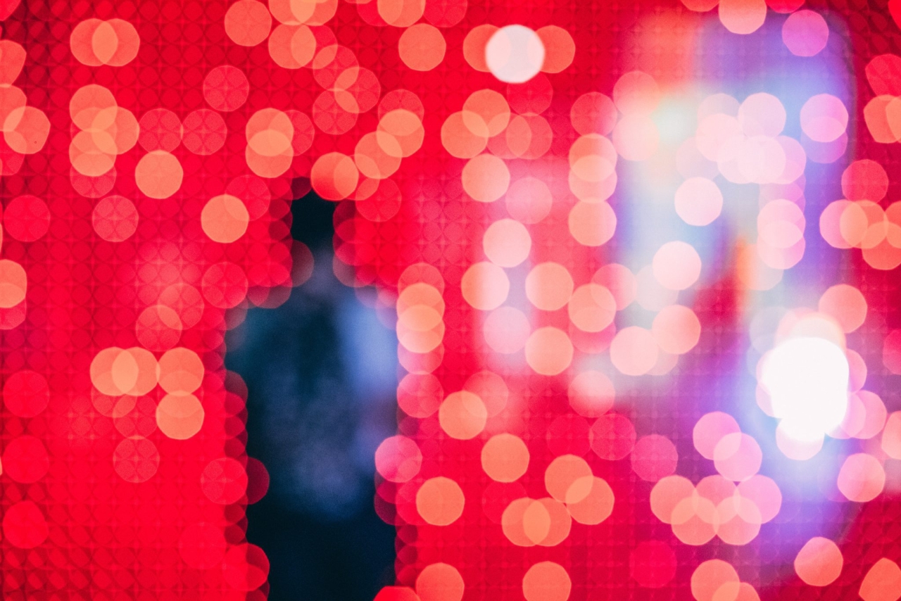 unfocused silhouette of a person in front of a field of pixelated red and blue lights
