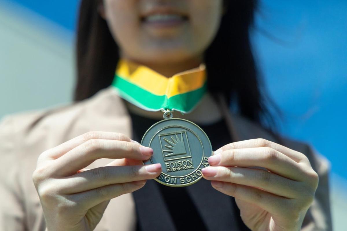 Edison Scholar Janna Lee holding out her medal