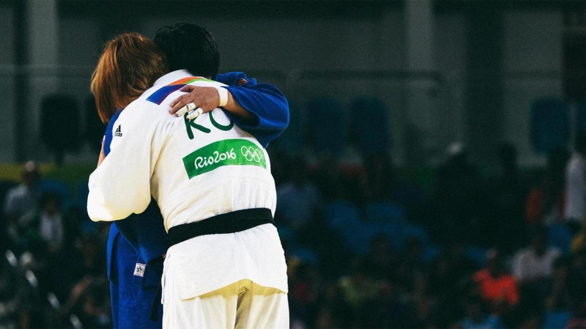 Two athletes hugging in an arena.