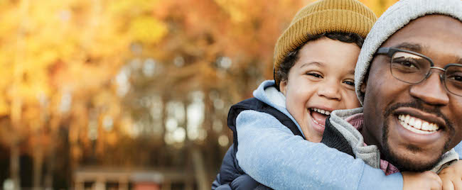 Man pictured with his son in front of a fall foliage scene.